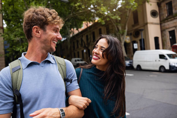 istock Young Couple Smiling While Strolling Together on City Street 2199082662