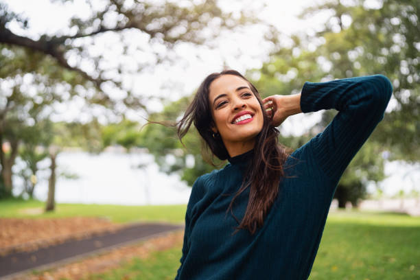 Woman Smiling Outdoors in a Park Under Natural Light