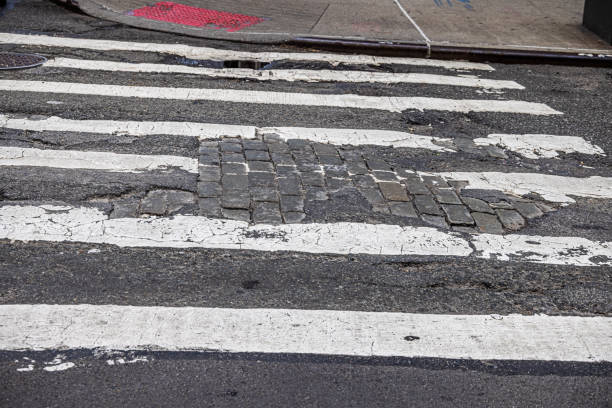The streets in some part of New York are very worn with plenty of potholes and a mixture of asphalt and cobblestones. The photograph is taken in the Lower Manhattan, New York.