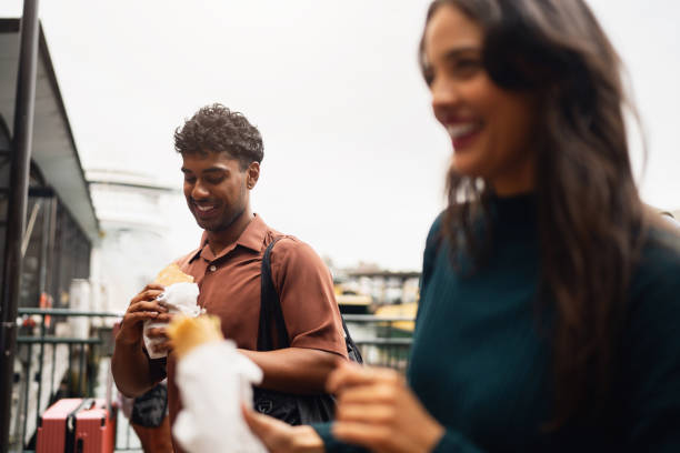 istock Two Smiling Friends Enjoying Outdoor Snacks in Urban Setting 2199083449
