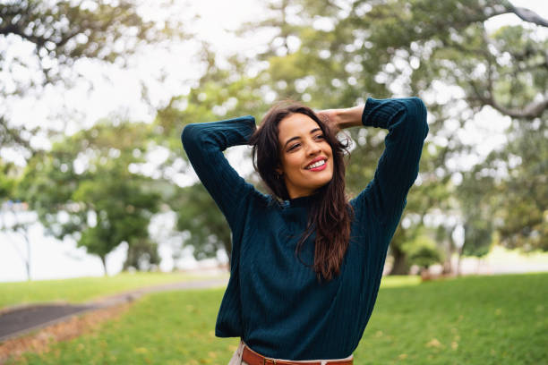 istock Young Woman Smiling in Park with Greenery and Trees in the Background 2199083571