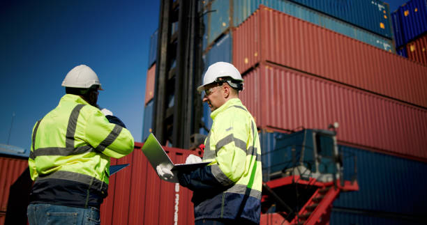 Logistic engineers and workers with a bright green safety jacket and safety PPE working at the container shipping yard