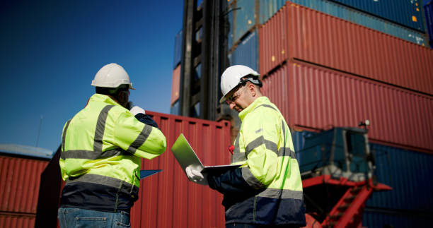 istock Logistic engineers and workers with a bright green safety jacket and safety PPE working at the container shipping yard 2199084731