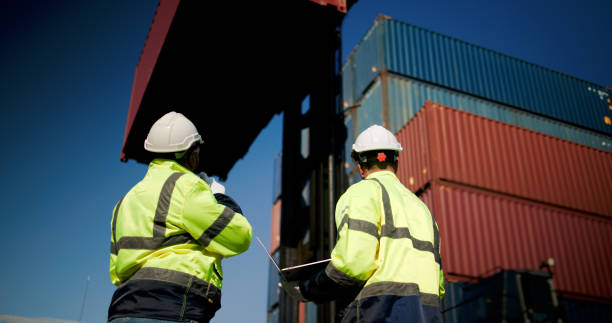 istock Logistic engineers and workers with a bright green safety jacket and safety PPE working at the container shipping yard 2199084734