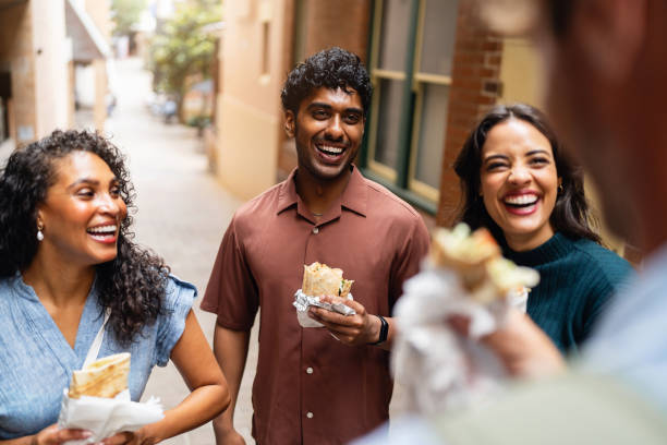 istock Group of Young Friends Sharing Laughter While Eating Outdoors 2199087027