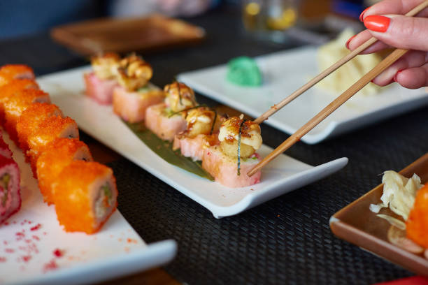 istock A woman's hand takes Japanese fish rolls 2199088259