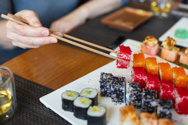 istock A woman's hand takes Japanese fish rolls 2199088278
