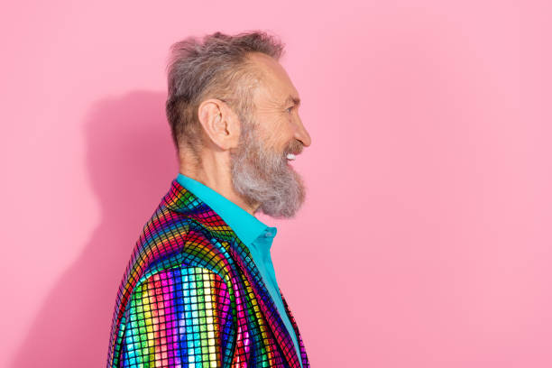istock Side profile of a stylish elderly man with a beard in a colorful striped jacket against a pink background 2199090435