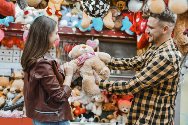 istock Affectionate Boyfriend Winning Teddy Bear For Girlfriend at Amusement Park While She's Looking Grateful 2199095082