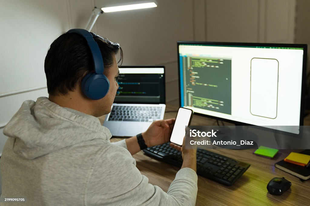 Smartphone Programmer Male Programmer Wearing Headphones Working At Home Comparing Smartphone ...