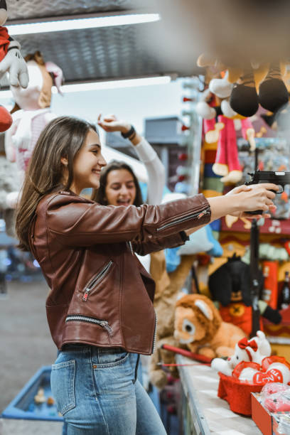 istock Female Holding Gun Aiming at Target With Smile While Friend is Cheering on Her With Raised Hand 2199095714
