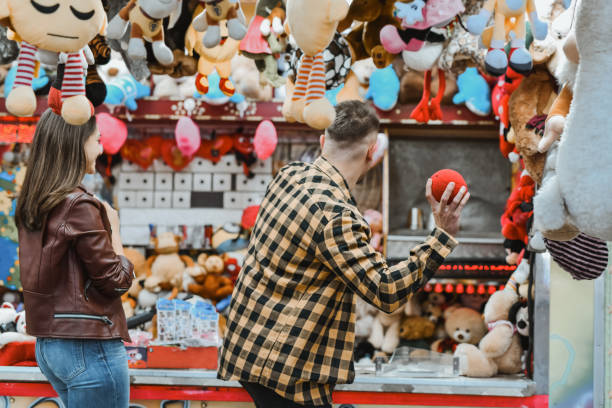 istock Focused Male Aiming Before Throwing Ball at Target Game While Girlfriend is Looking at Him 2199096046