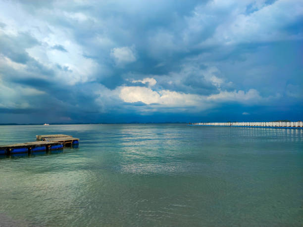 The white walkway pontoon with beautiful white clouds sky and blue turquoise sea.