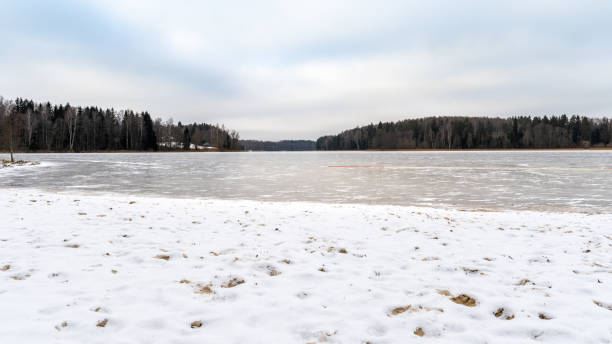 istock Frozen Lake with Snowy Shoreline and Forest in Winter Landscape 2199103207