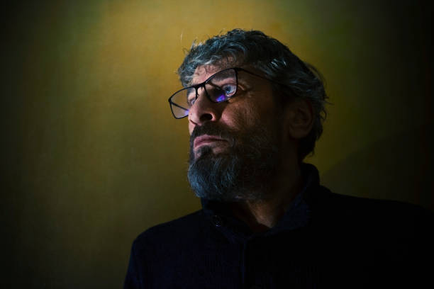 Expressive portrait of a middle-aged man, wearing glasses, with a worried and interested expression on his face.
