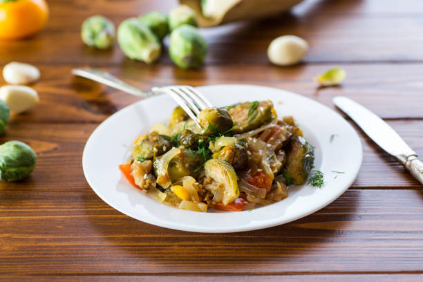 istock Brussel sprouts cooked with vegetables and spices, on a wooden table 2199104954
