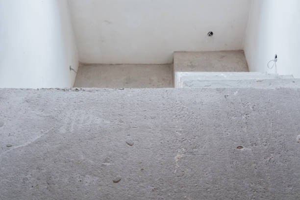 A concrete stairwell features a simple design with white walls above.