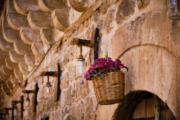 Flowers in a wicker basket and lamps hanging on stone wall. Street decoration. Hanging basket full of flowers