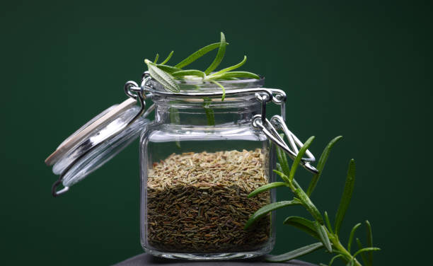 Rosemary in glass storage bottle with green background