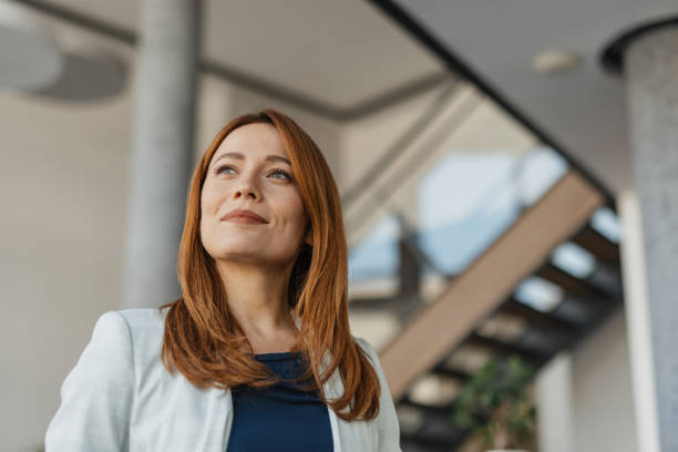 istock Confident woman looking upwards in a bright room. 2199111973