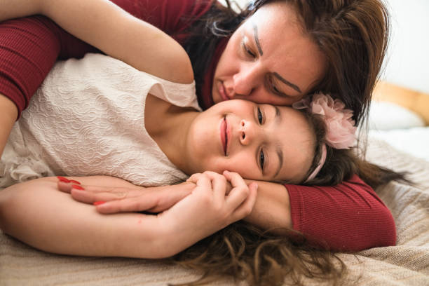 istock mom and daughter having fun on the bed 2199116312