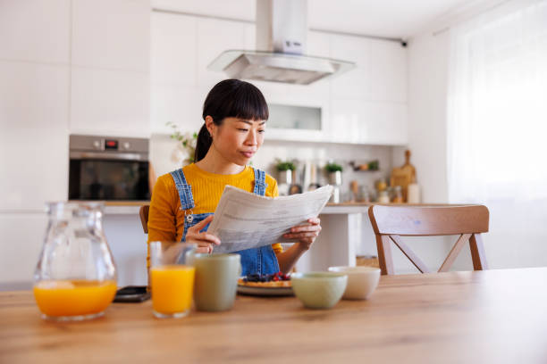 istock Woman reading newspaper and having breakfast at home 2199116933