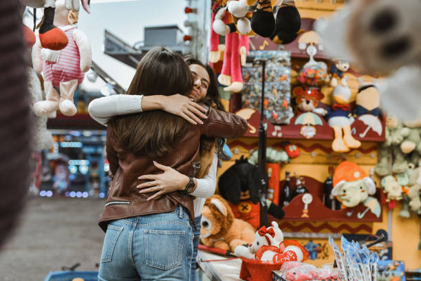 istock Affectionate Sisters Hugging Each Other at Amusement Park After Winning in Target Shooting Game 2199118943