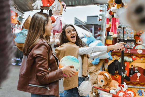 istock Joyful Female Laughing Loudly While Aiming and Missing Target At Amusement Park Shooting Game 2199119960