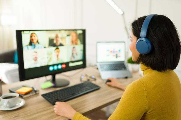 istock Female freelancer wearing headphones working remotely, participating in virtual team meeting via desktop computer 2199120006