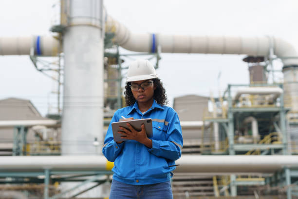 istock Female engineers work with tablet in gas refineries and oil refinery plants to check production quality and safety of refineries. 2199121744