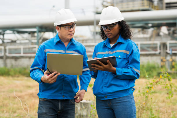 istock Male and female engineers work using laptop and tablet in gas refineries and oil refinery plants to check production quality and safety of refineries. 2199122002