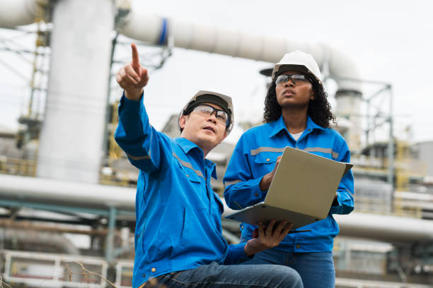 istock Male and female engineers work using laptop and tablet in gas refineries and oil refinery plants to check production quality and safety of refineries. 2199122003