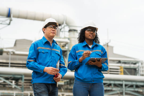 istock Male and female engineers work using laptop and tablet in gas refineries and oil refinery plants to check production quality and safety of refineries. 2199122016