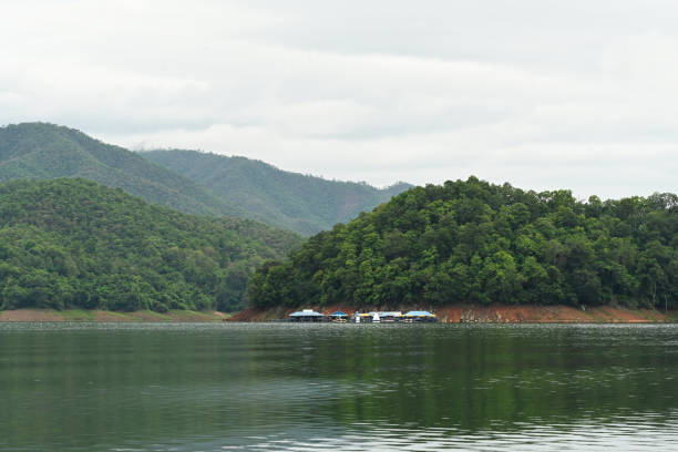A tranquil lakeside scene featuring lush green hills, misty mountains, and calm water, offering a peaceful retreat in nature's embrace.
