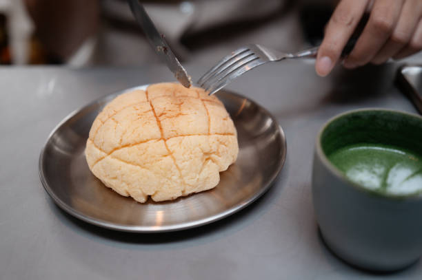 Asian woman holding cutlery and fork before eating Melon pan served on plate