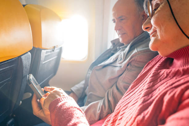 istock Senior Couple Using A Phone Together While Riding In An Airplane 2199125613