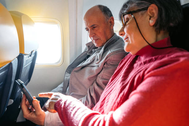 istock Senior Couple Using A Phone Together While Riding In An Airplane 2199125622