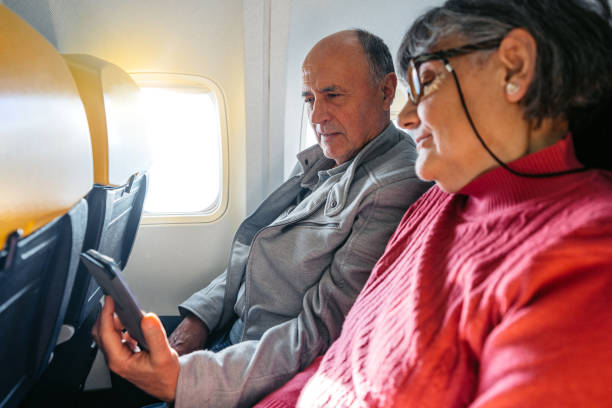 istock Senior Couple Using A Phone Together While Riding In An Airplane 2199125767