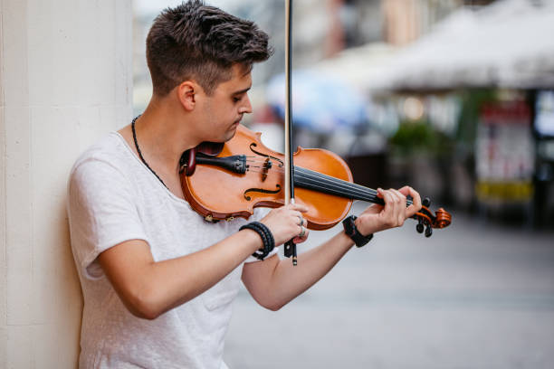 Handsome young man playing a violin on the street.