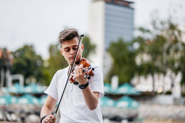 Handsome young man playing a violin on the quayside.