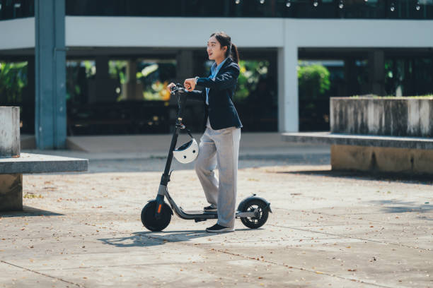 istock Professional female entrepreneur checking time while balancing on electric scooter, riding through contemporary cityscape, rushing between work commitments 2199127076