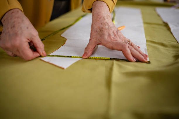 istock Senior woman creating clothing patterns in her tailoring studio with measuring tape and fabric 2199128311