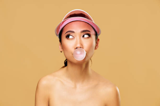 istock Trendy young woman blowing bubble gum on beige background. 2199128550