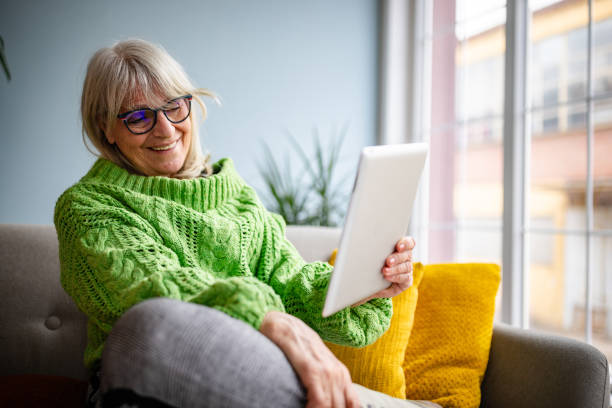 istock Senior woman enjoying a cozy moment at home using a tablet while relaxing on a comfortable sofa in a serene living room 2199129968