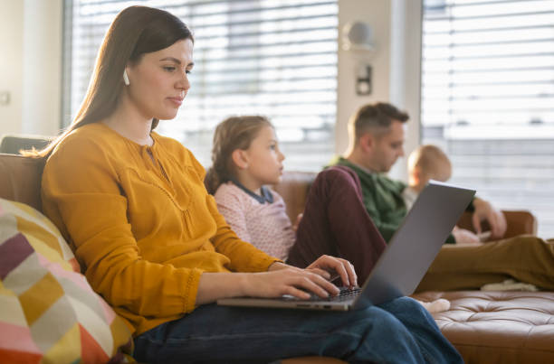 istock Young Family Sitting On Couch Absorbed In Digital Devices 2199131582