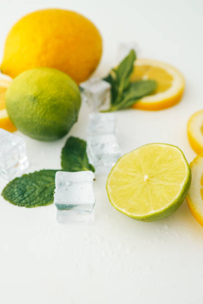 istock Fresh lime and lemon halves with mint leaves and ice cubes on a white background. A vibrant composition showcasing citrus fruits, perfect for healthy food, drinks, or summer themes 2199132107