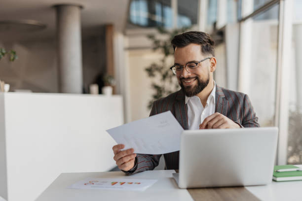 istock Smiling Professional Reviewing Reports at Desk 2199132393