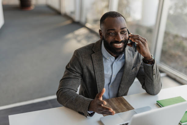 istock Happy man engaged in a call while at his desk 2199132952