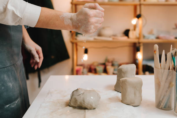 istock Female potter rolls piece of clay before sculpting. Preparing clay for making ceramic crockery. 2199135280