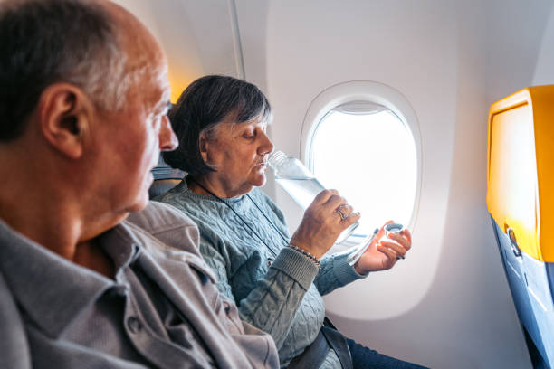 istock Senior Woman Drinking Water While Riding In An Airplane 2199136517